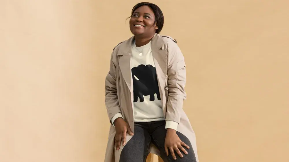 The Black Sheep sweatshirt worn with a trench coat, photographed on a model